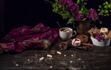 Bir eski akan mor şeffaf eşarp oryantal tarzı ahşap bir masada kahve ve bakır bir dokuma vazoda macaroons.