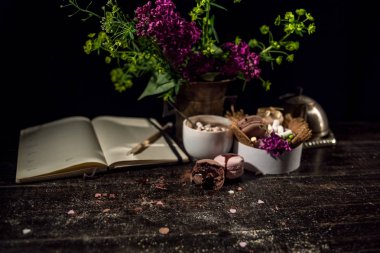 Kahve fincanı altında bazı macarons yığını ile Lila ve yeşil bitki vazo ile boş Not