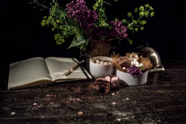 Kahve fincanı altında bazı macarons yığını ile Lila ve yeşil bitki vazo ile boş Not