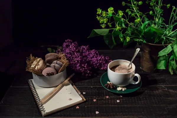Kahve fincanı altında bazı macarons yığını ile Lila ve yeşil bitki vazo ile boş Not