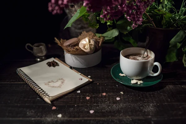Note vierge avec tasse à café sous vase avec lilas et plante verte avec une pile de macarons — Photo