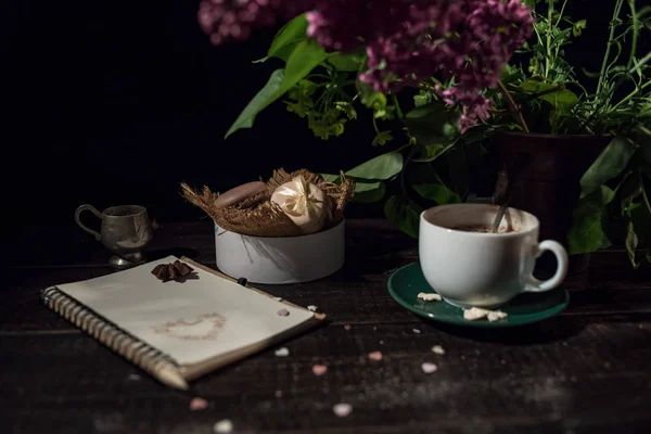 Kahve fincanı altında bazı macarons yığını ile Lila ve yeşil bitki vazo ile boş Not