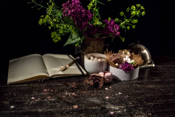 Kahve fincanı altında bazı macarons yığını ile Lila ve yeşil bitki vazo ile boş Not