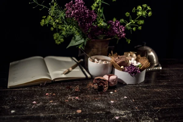 Kahve fincanı altında bazı macarons yığını ile Lila ve yeşil bitki vazo ile boş Not