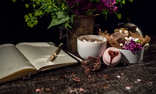 Kahve fincanı altında bazı macarons yığını ile Lila ve yeşil bitki vazo ile boş Not