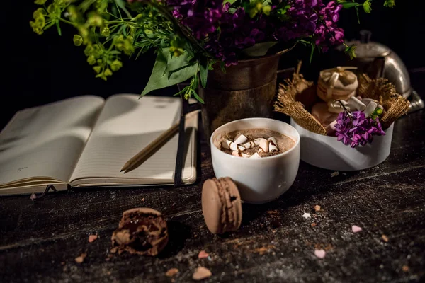 Blank note with coffee cup under vase with lilac and green plant with some macarons stack — Stock Photo, Image