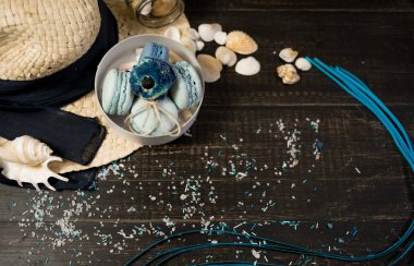 Mavi macaroons ve ahşap zemin üzerine kabukları ile deniz tuzu ile hasır şapka