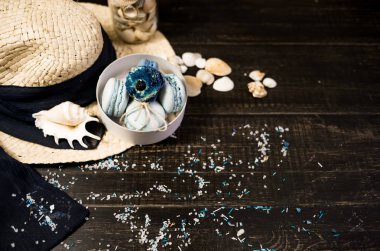 Mavi macaroons ve ahşap zemin üzerine kabukları ile deniz tuzu ile hasır şapka