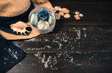 Mavi macaroons ve ahşap zemin üzerine kabukları ile deniz tuzu ile hasır şapka