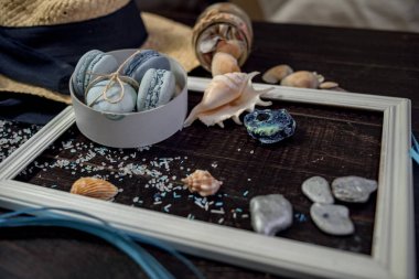 Mavi macaroons ve ahşap zemin üzerine kabukları ile deniz tuzu ile hasır şapka