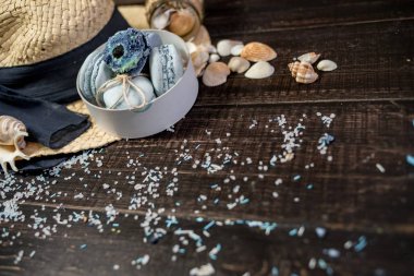 Mavi macaroons ve ahşap zemin üzerine kabukları ile deniz tuzu ile hasır şapka