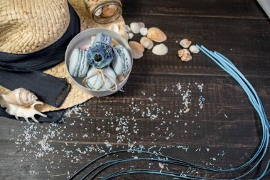 Mavi macaroons ve ahşap zemin üzerine kabukları ile deniz tuzu ile hasır şapka