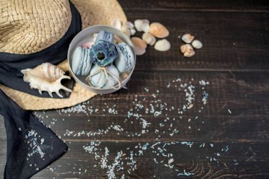 Mavi macaroons ve ahşap zemin üzerine kabukları ile deniz tuzu ile hasır şapka
