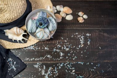 Mavi macaroons ve ahşap zemin üzerine kabukları ile deniz tuzu ile hasır şapka