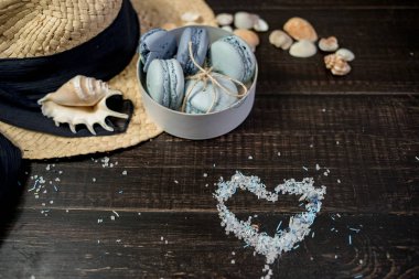 Mavi macaroons ve ahşap zemin üzerine kabukları ile deniz tuzu ile hasır şapka