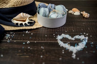 Mavi macaroons ve ahşap zemin üzerine kabukları ile deniz tuzu ile hasır şapka