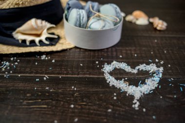 Mavi macaroons ve ahşap zemin üzerine kabukları ile deniz tuzu ile hasır şapka