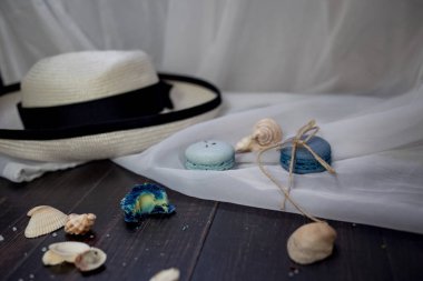 Mavi macaroons ve ahşap zemin üzerine kabukları ile deniz tuzu ile hasır şapka