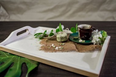 Bir fincan kahve çiçek kiraz ve monstera yaprak dalı ile beyaz bir tepsi