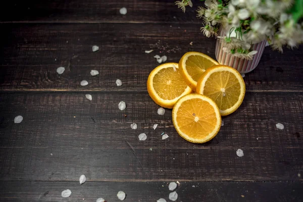 Macaroons multicoloridos de cor branca e laranja com frutas laranja fatiadas em um fundo de madeira com alguns doces esmagados e cereja flor — Fotografia de Stock