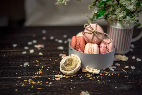 Pot blanc avec une branche de fleurs de cerisier et de macarons dans un plat profond blanc — Photo