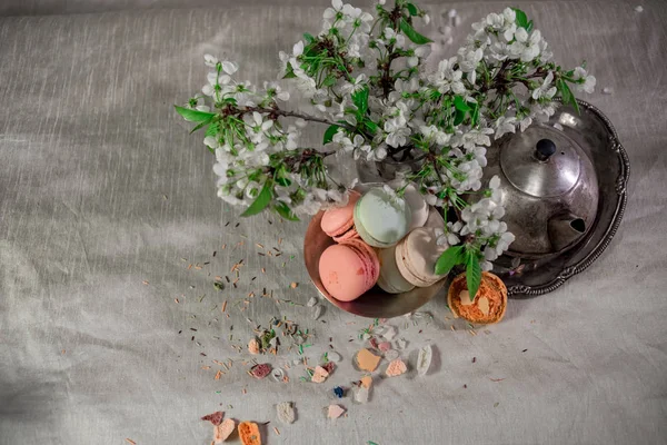 Macarons multicoloridos em vaso de prata metálico e chaleira de prata em um fundo pastel — Fotografia de Stock