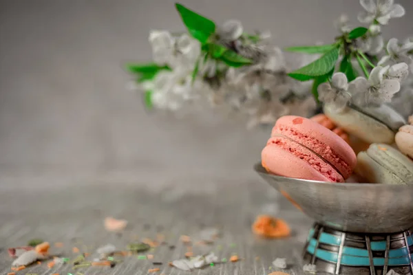 Multocolored macarons in metal silver vase on a pastel background — Stock Photo, Image