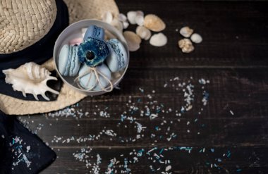 Mavi macaroons ve ahşap zemin üzerine kabukları ile deniz tuzu ile hasır şapka