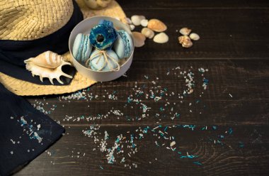 Mavi macaroons ve ahşap zemin üzerine kabukları ile deniz tuzu ile hasır şapka