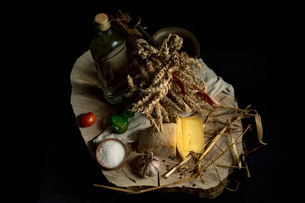Домашний сыр Kraft на темном фоне с овощами и бутылками на деревянном столе — стоковое фото