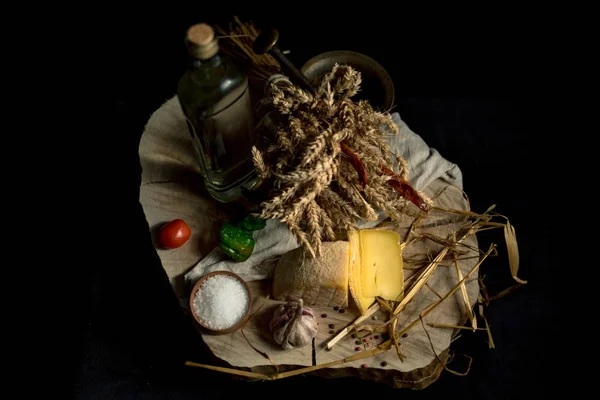 Queijo caseiro Kraft no fundo escuro com legumes com garrafas na mesa de madeira — Fotografia de Stock