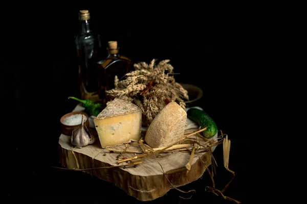 Queijo caseiro no fundo escuro com legumes com garrafas na mesa de madeira — Fotografia de Stock