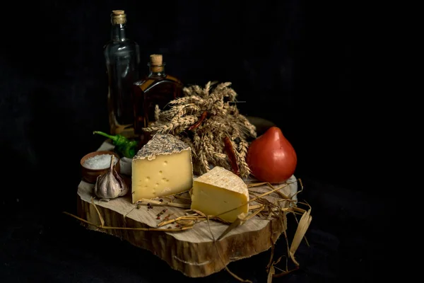 Queso casero Kraft sobre fondo oscuro con verduras y botellas sobre mesa de madera — Foto de Stock