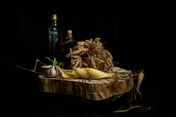 Домашний сыр Kraft на темном фоне с овощами и бутылками на деревянном столе — стоковое фото