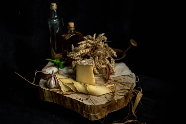 Queijo caseiro no fundo escuro com legumes com garrafas na mesa de madeira — Fotografia de Stock