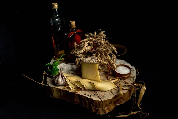 Queso casero Kraft sobre fondo oscuro con verduras y botellas sobre mesa de madera — Foto de Stock