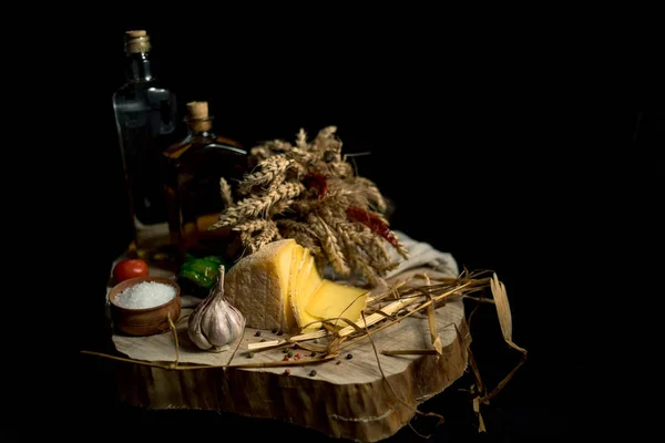 Queso casero Kraft sobre fondo oscuro con verduras y botellas sobre mesa de madera —  Fotos de Stock