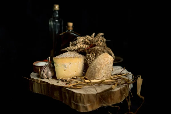 Homemade cheese on the dark background with vegetables with bottles on wood table — Stock Photo, Image