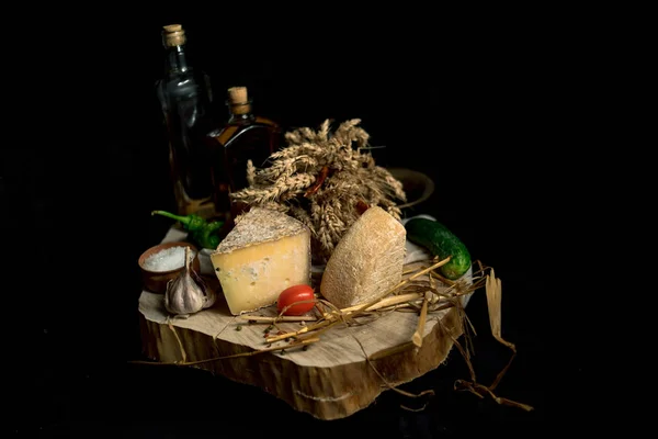 Kraft homemade cheese on the dark background with vegetables with bottles on wood table — Stock Photo, Image