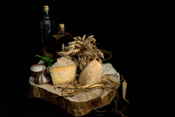 Queso casero Kraft sobre fondo oscuro con verduras y botellas sobre mesa de madera —  Fotos de Stock