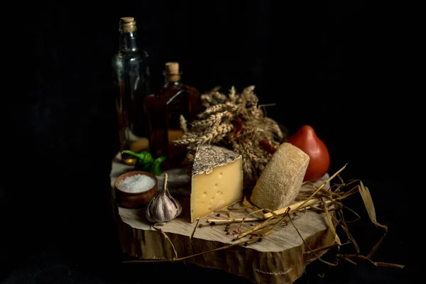 Queijo caseiro Kraft no fundo escuro com legumes com garrafas na mesa de madeira — Fotografia de Stock