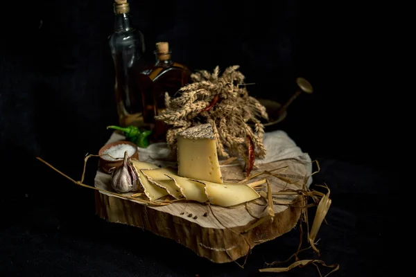 Kraft homemade cheese on the dark background with vegetables with bottles on wood table — Stock Photo, Image