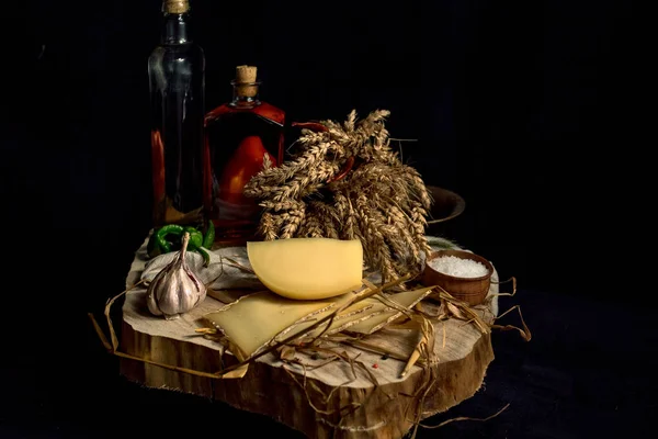 Kraft homemade cheese on the dark background with vegetables with bottles on wood table