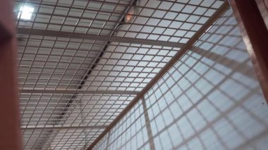 Hapishane koridorundaki metal parmaklıklar bir ampulün arka planına karşı..