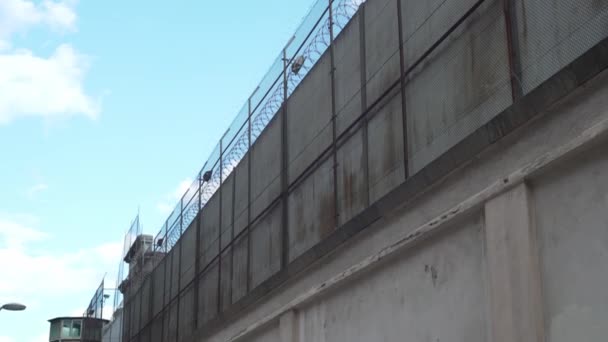 Очень высокий тюремный забор с колючей проволокой против ясного неба — стоковое видео