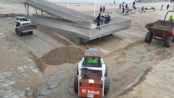 Een tractor laadt zand in een vuilniswagen tijdens een strandherstel na een storm. — Stockvideo