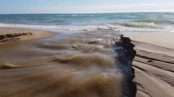 Een waterstroom vernietigt het zeestrand na zware regenval. — Stockvideo