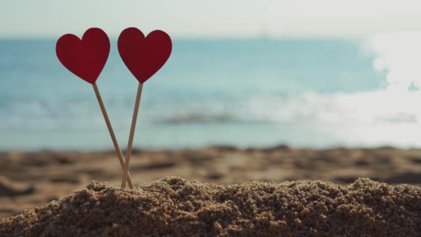 Dos hermosos corazones de madera en el fondo del mar en la arena en la playa — Vídeos de Stock