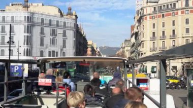 İnsanlar kışın güneşli bir havada Barselona caddesinde turist otobüsüne biniyorlar.