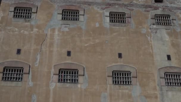 Antiguo muro de piedra de un edificio de la prisión con pequeñas ventanas con barras . — Vídeos de Stock